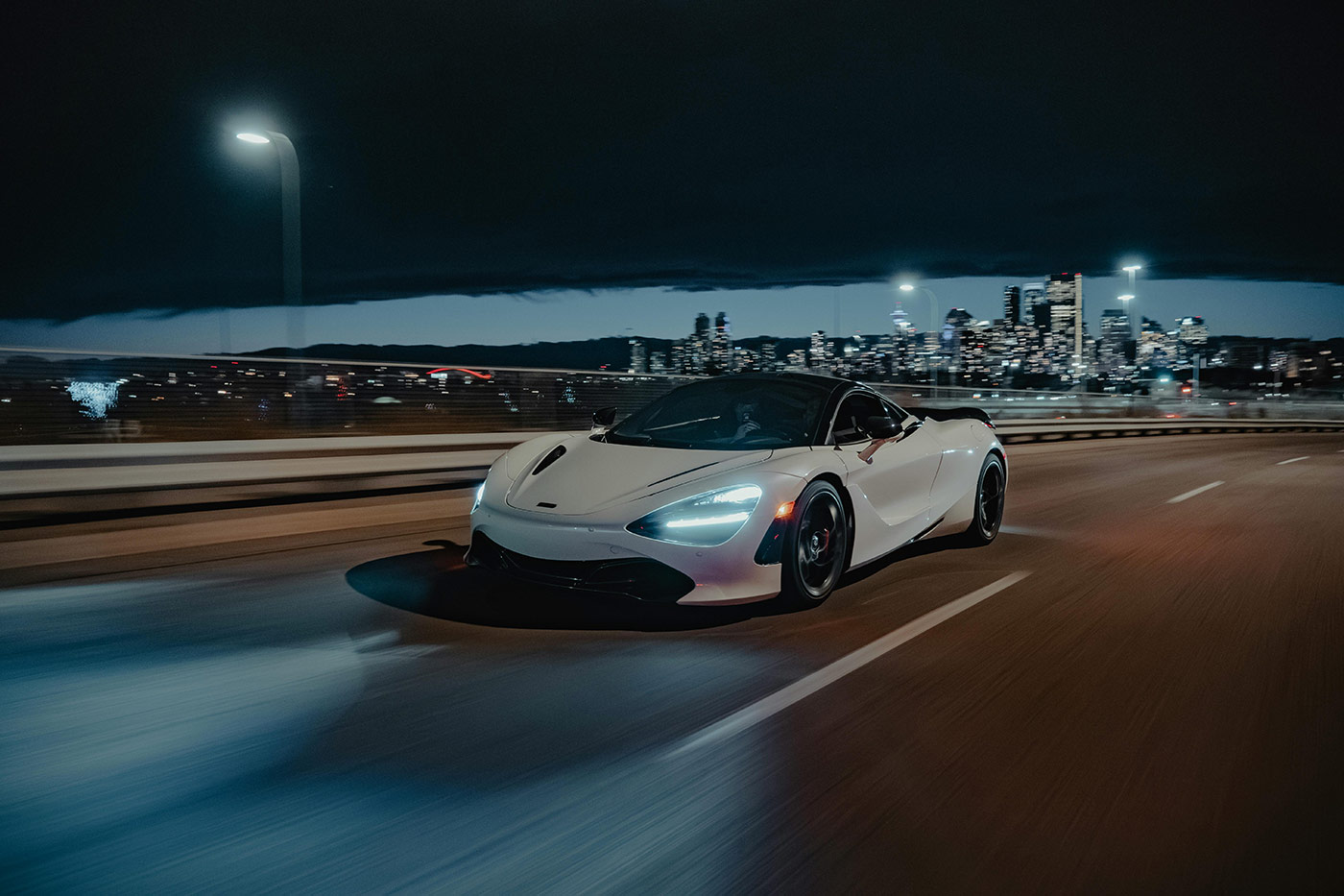 White supercar driving at high speed through a city at night, representing Steelhead’s lightweight composite accumulators used in elite motorsport and OEM vehicles to enhance suspension, braking, and energy recovery performance.