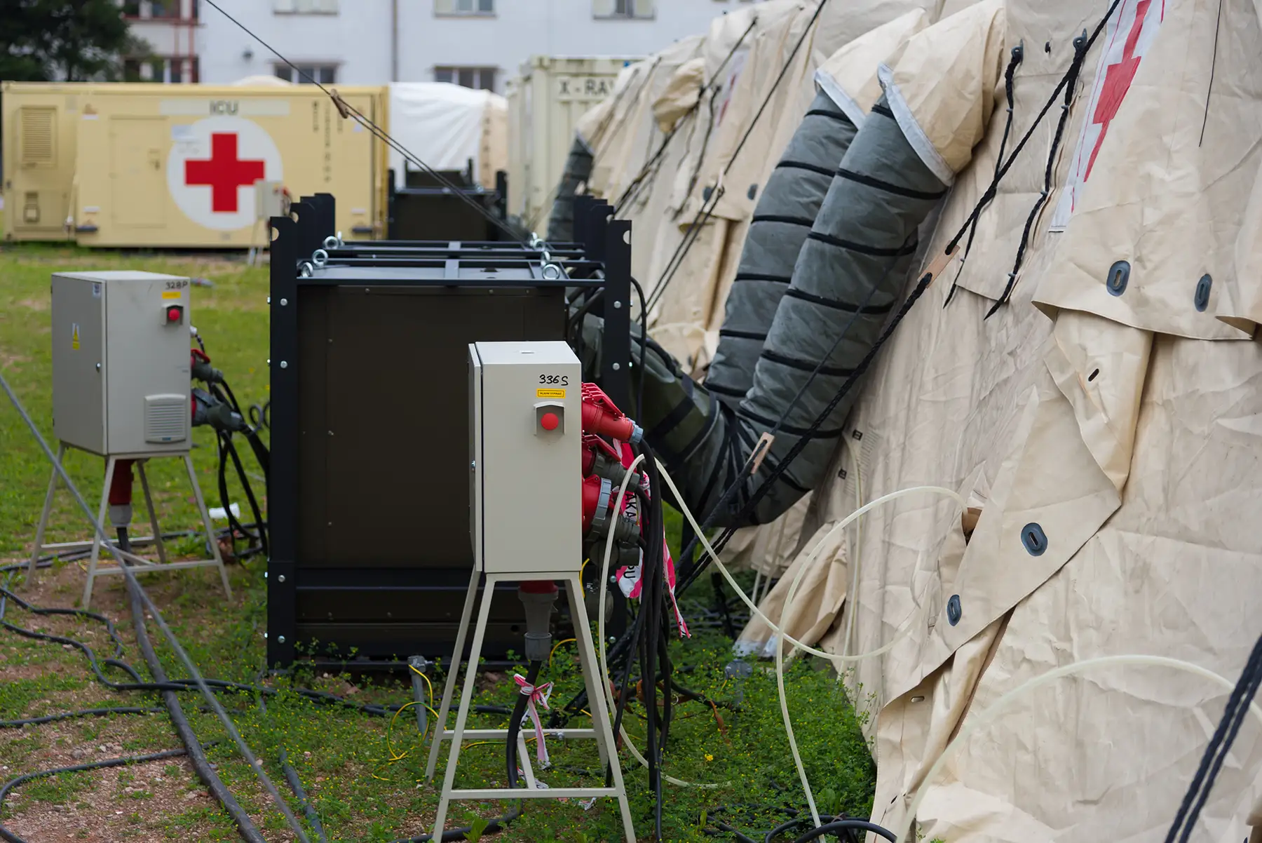 Field-deployed military support site with interconnected environmental control units, power distribution panels, and tented medical or operations shelters, illustrating the type of mobile infrastructure where Steelhead composite pressure vessels integrate into defense breathing-air and hydrogen generation systems.
