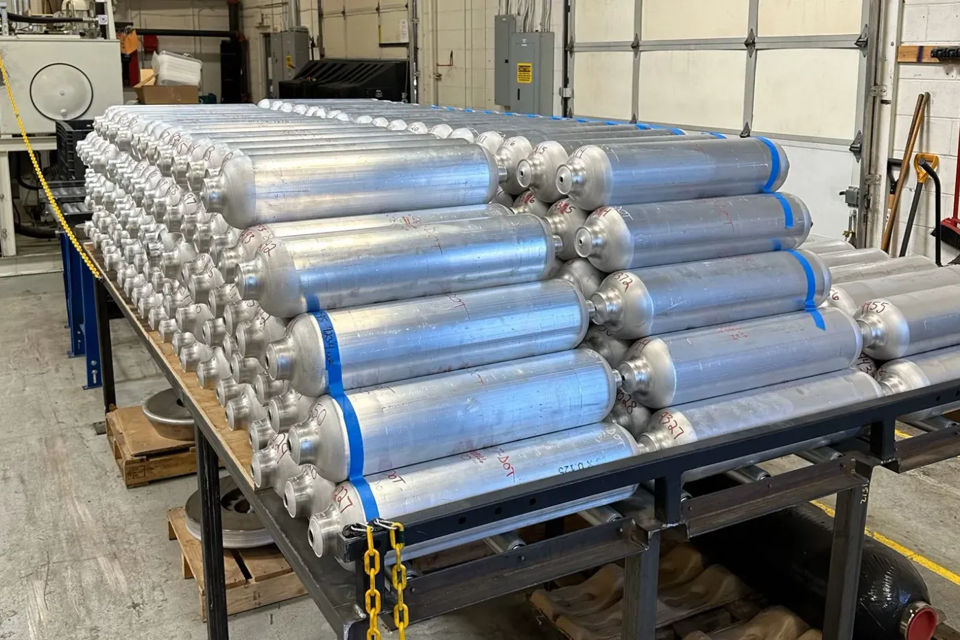 Stacks of seamless aluminum liners (Type 3) prepared for composite overwrapping in advanced pressure vessel fabrication.